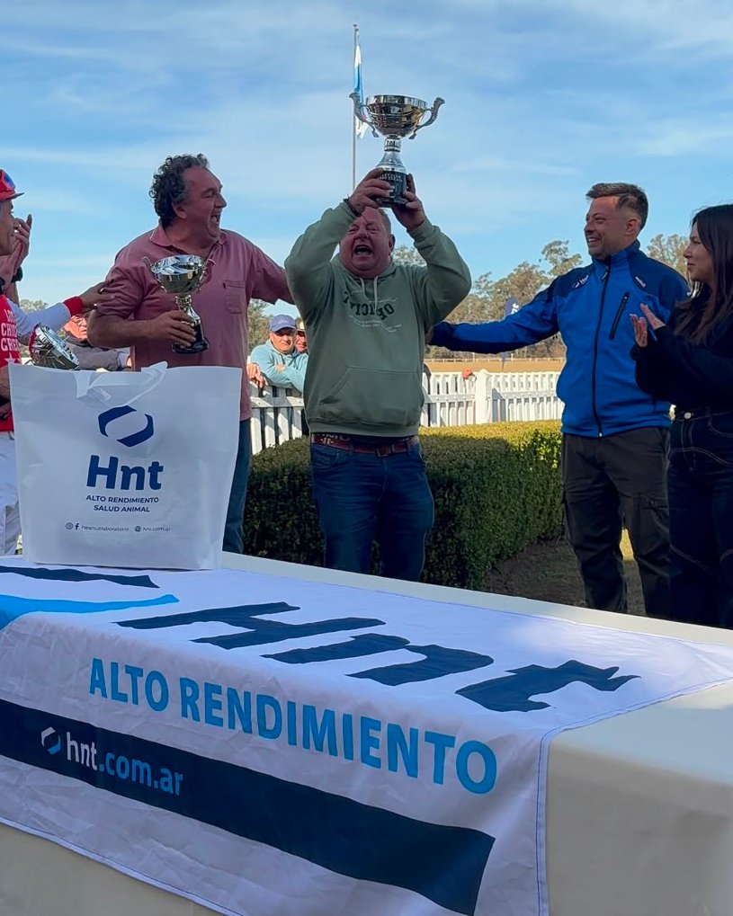Integrante del equipo ganador levanta la copa del Súper Clásico Laboratorio HNT sobre la mesa de premiación