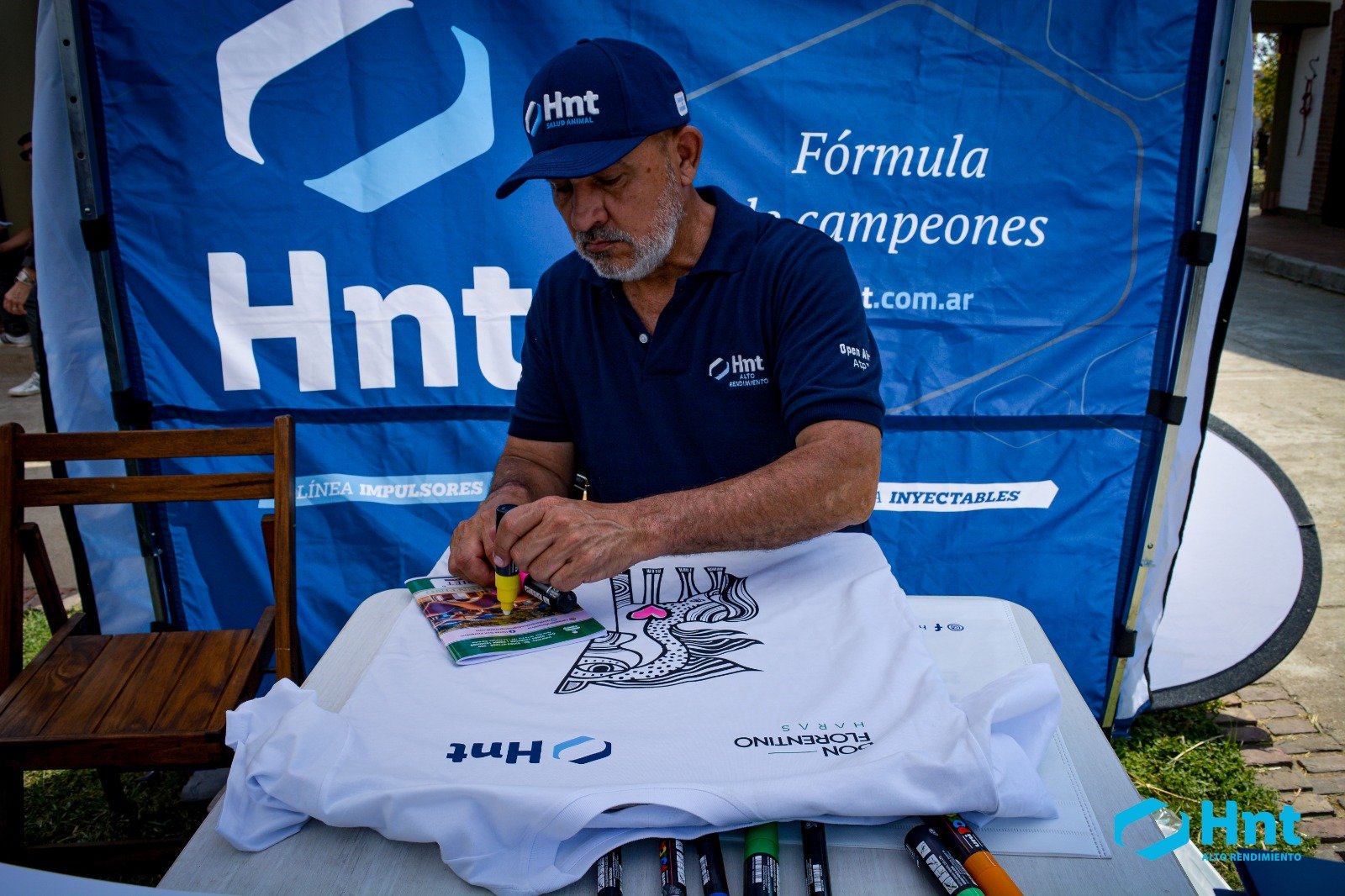 Integrante de HNT colorea una remera ilustrada por Mario Lange en el stand del laboratorio